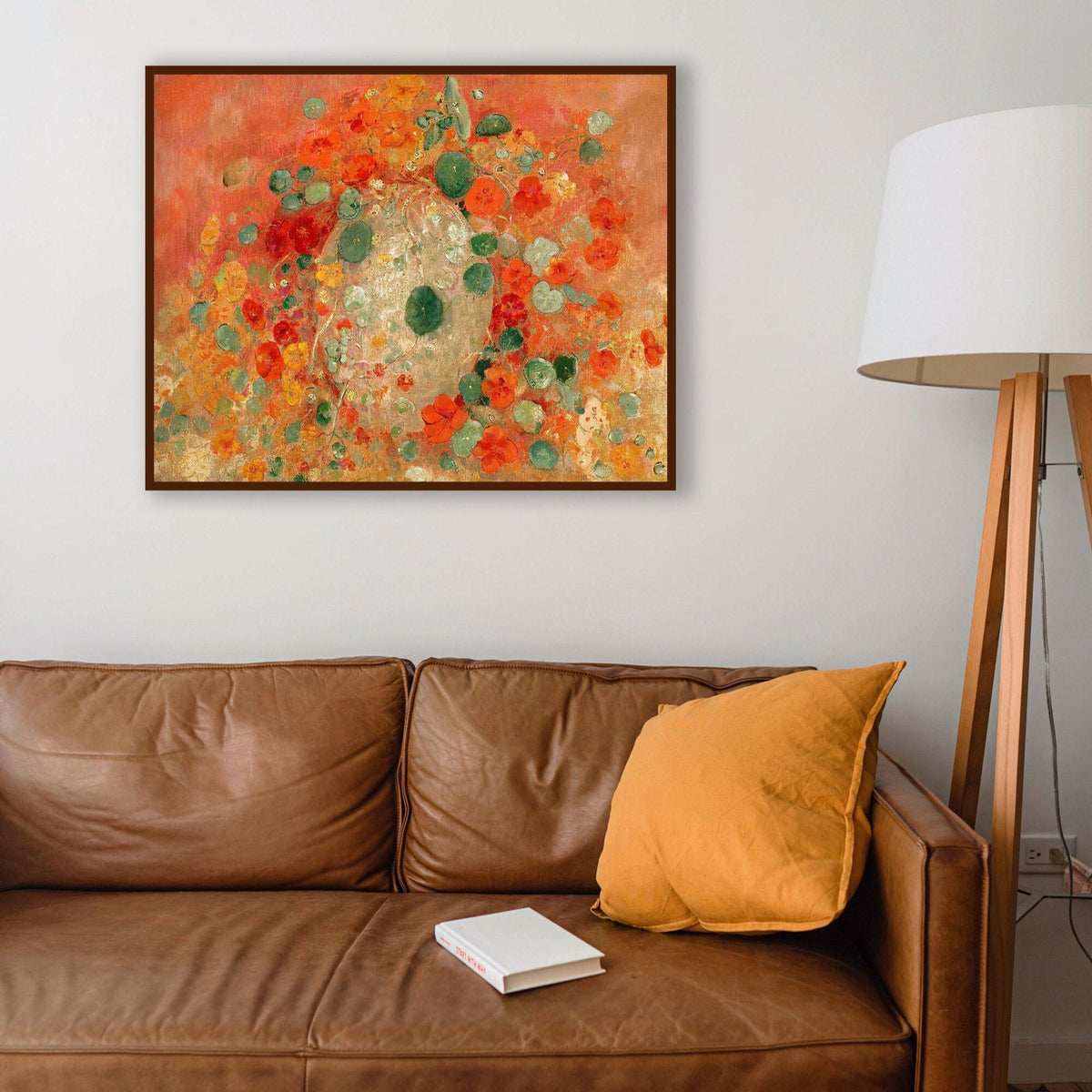 A fine art print of Odilon Redon's oil painting, Nasturtiums, from 1905, framed in a thin, black picture frame and hung in a modern living room above a leather sofa.