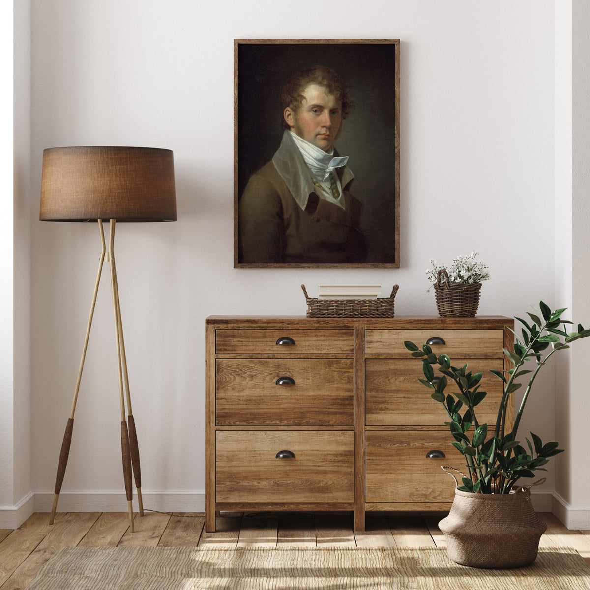 Wooden dresser with a lamp, plant, and portrait of a gentleman, in a room.