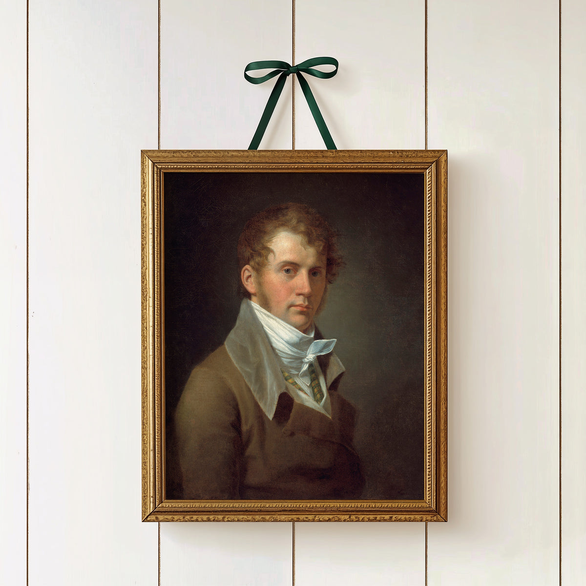 Framed portrait of a man in a white cravat, hanging on a white paneled wall.