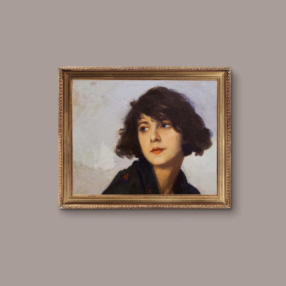 Framed portrait of a woman with a gold frame on a beige wall