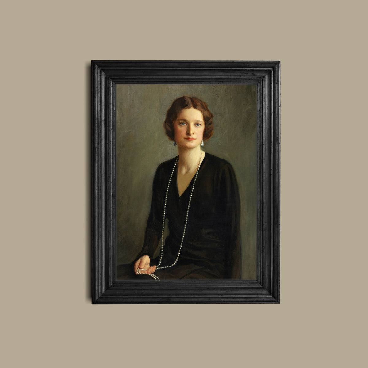 A fine art print of a beautiful portrait from the Art Deco period. The print is displayed hanging on a wall in a black picture frame.