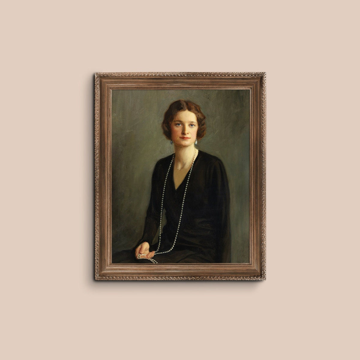 A fine art print of a beautiful portrait from the Art Deco period. The print is displayed hanging on a dusky pink wall in an ornate wooden picture frame.