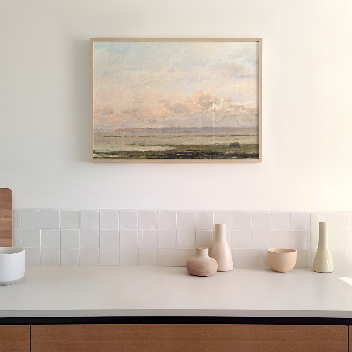 Framed landscape print above a kitchen counter with decorative vases.