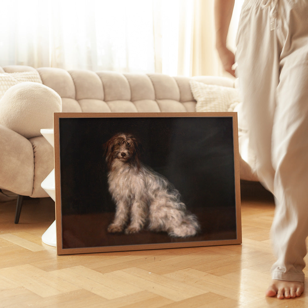 Framed artwork of a dog on a dark background in a living room with wooden flooring and lady walking by.