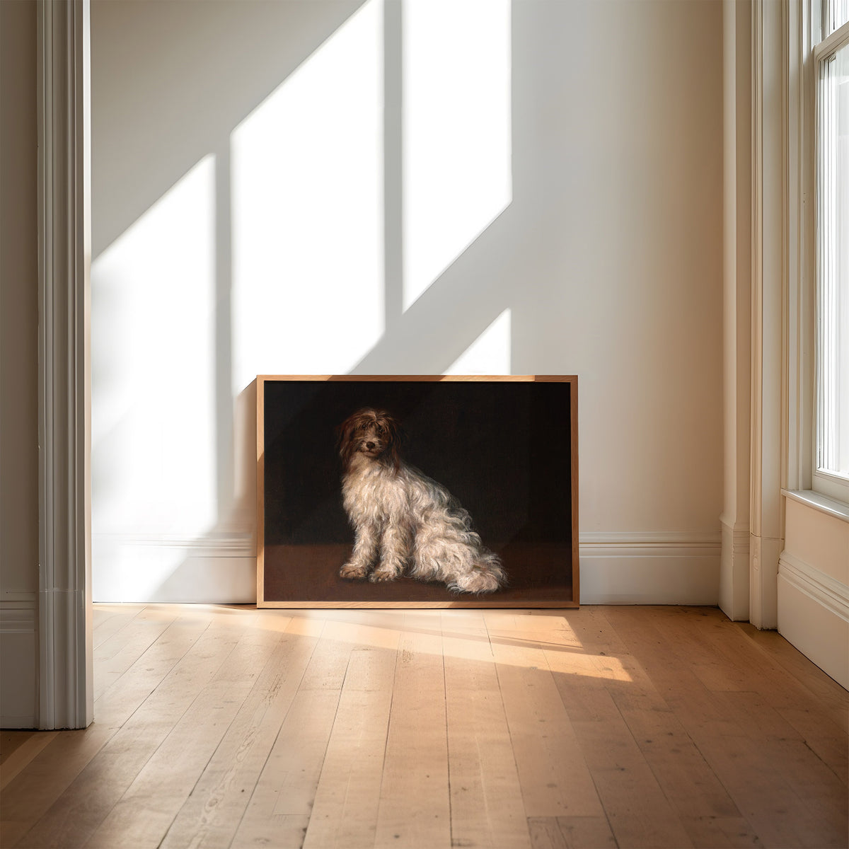 Framed artwork of a terrier dog painted on a dark background in a room with wooden flooring and light streaming in through the window.
