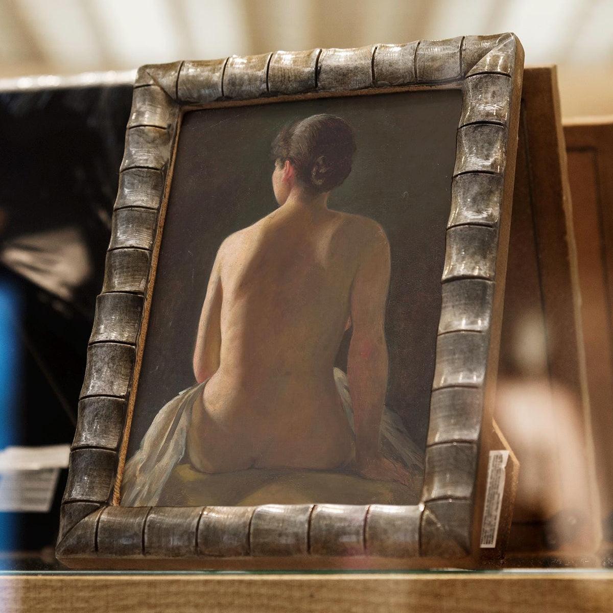 Framed print of a nude figure sitting with an ornate frame.