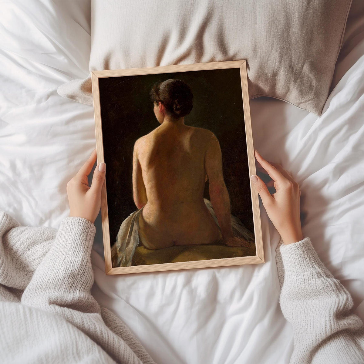 Person holding a framed print of a nude figure on a bed.