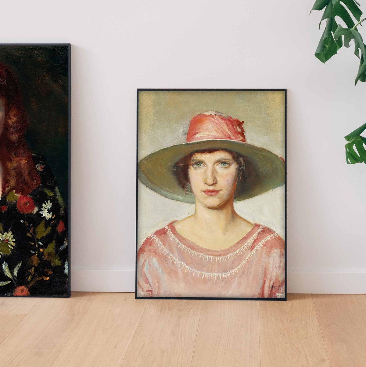 A fine art print of an Art Deco oil painting of a portrait of a lady. The print is displayed in a thin black frame resting on the floor, leaning up against a wall.