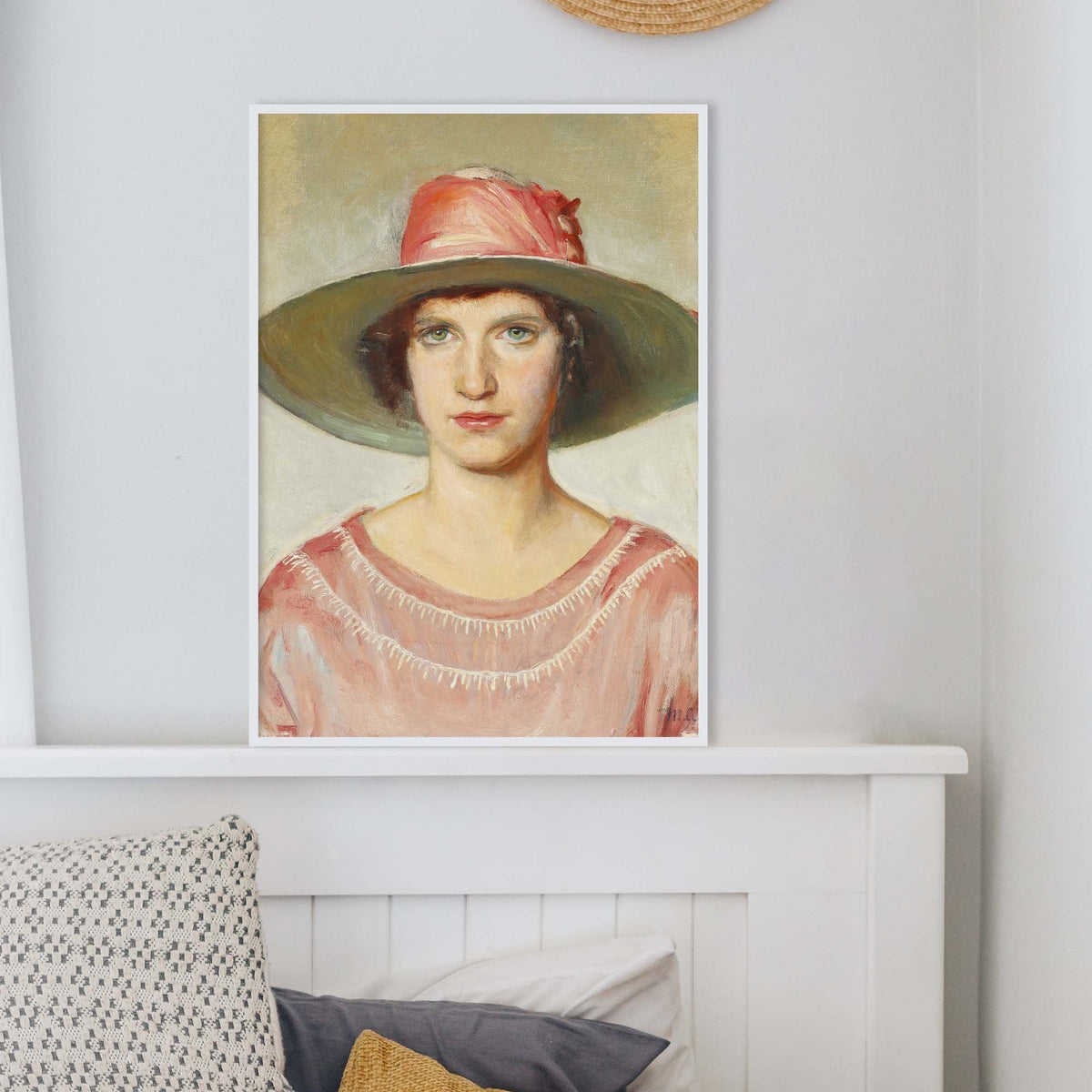 A fine art print of an Art Deco oil painting of a portrait of a lady. The print is displayed in a thin white frame resting on top of a headboard.
