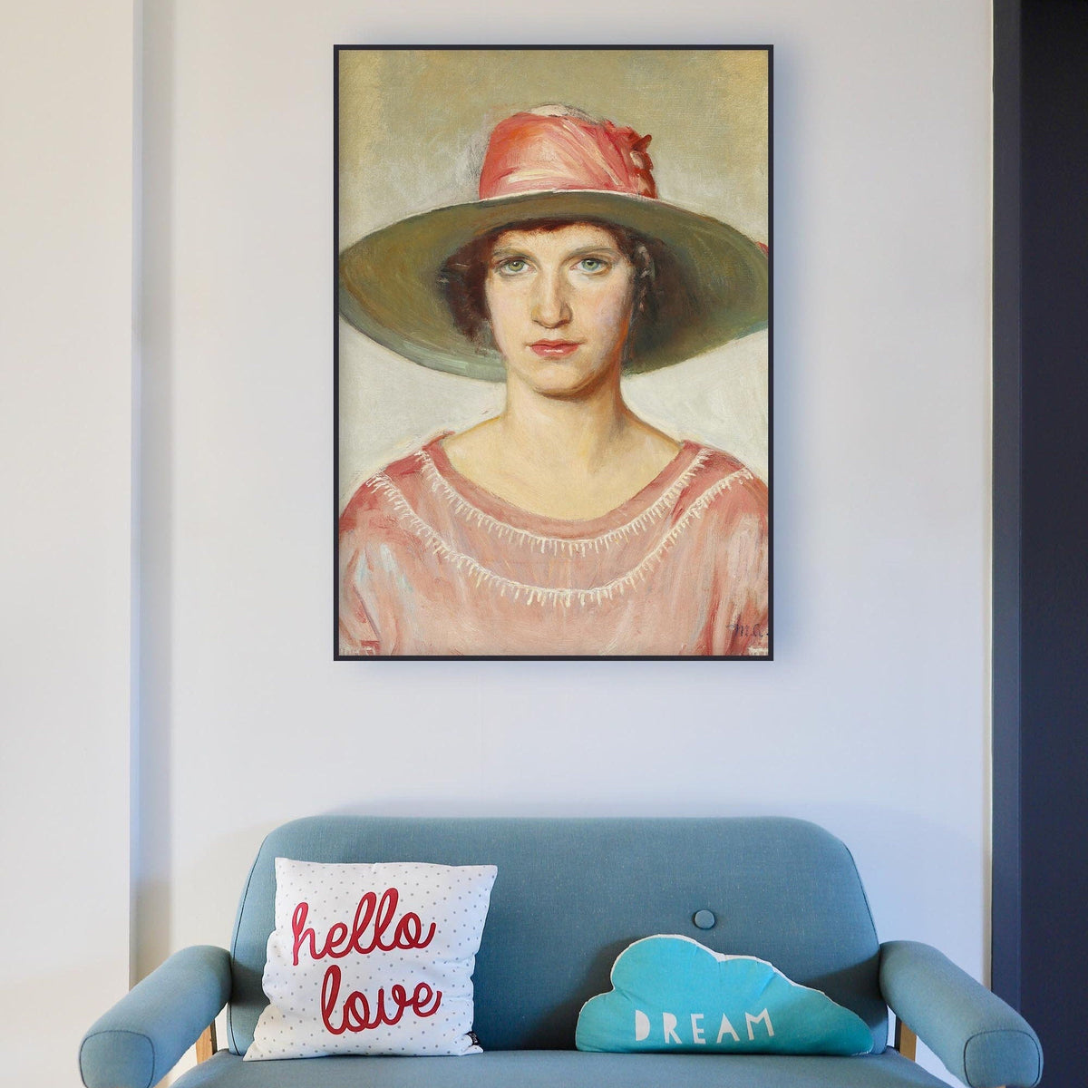 Blue sofa with decorative pillows and a framed female portrait on the wall.