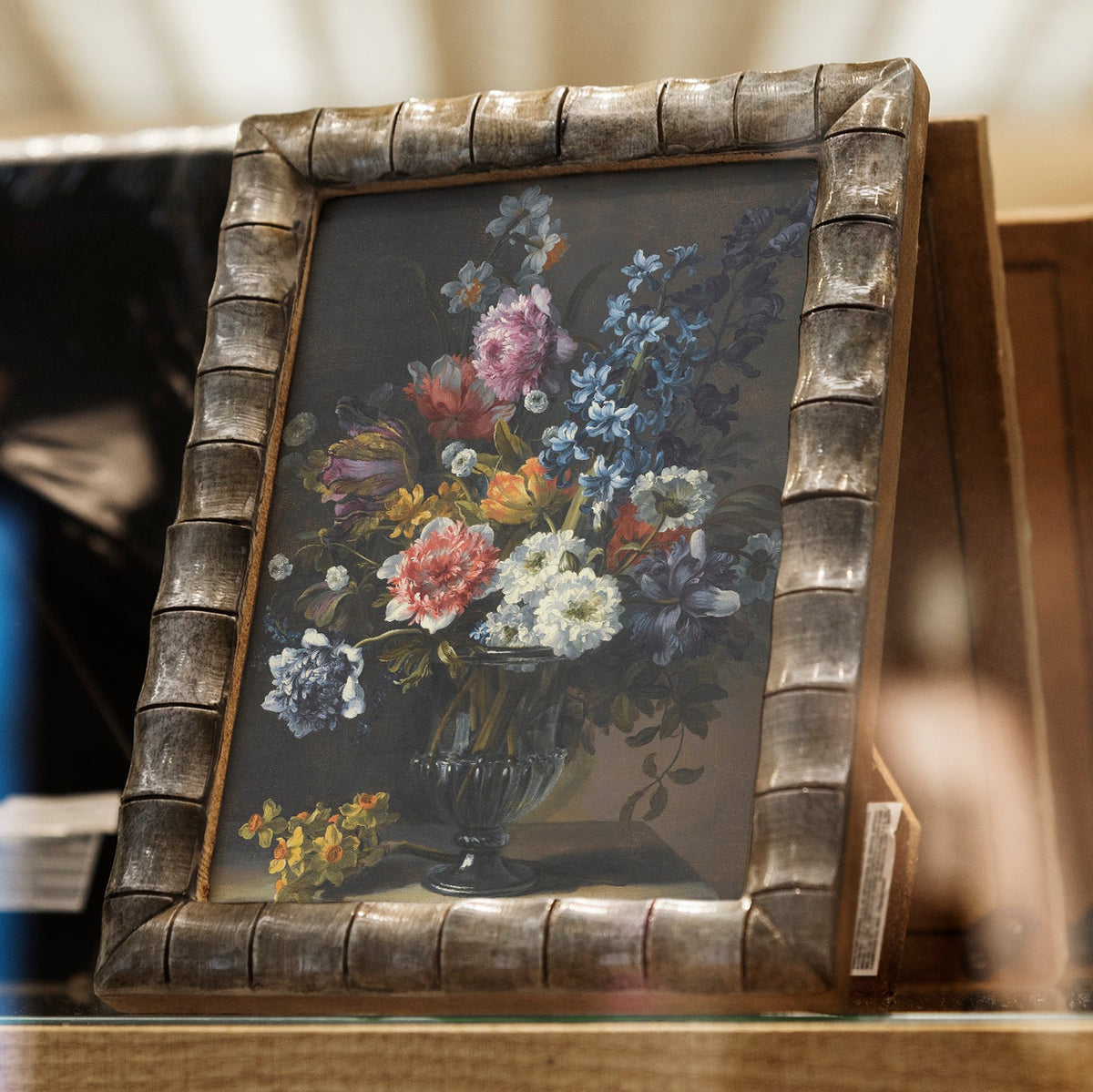Framed floral print on a wooden shelf.