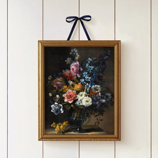 Gold-framed print of a floral arrangement on a white paneled wall, hung with a ribbon.