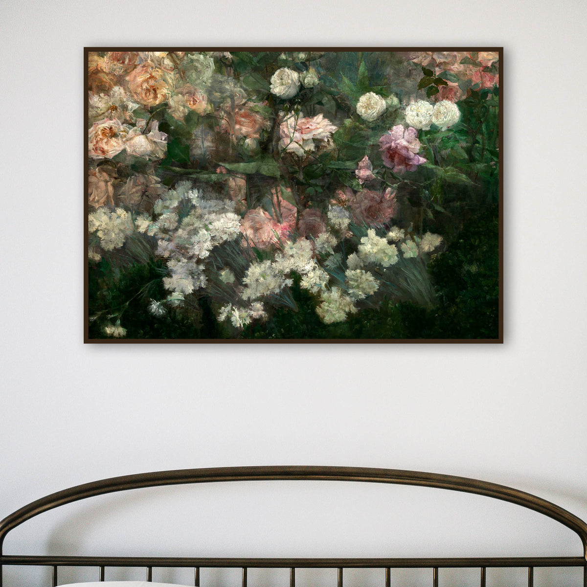 A framed art print of a rose garden in full bloom, hanging above a metal bedframe on a white wall.