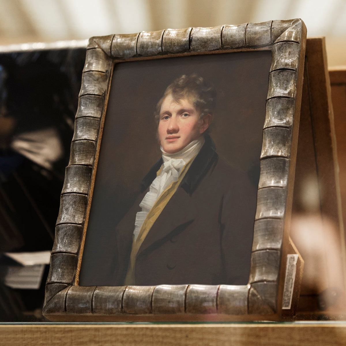 Portrait of a man in a decorative frame on a wooden shelf.