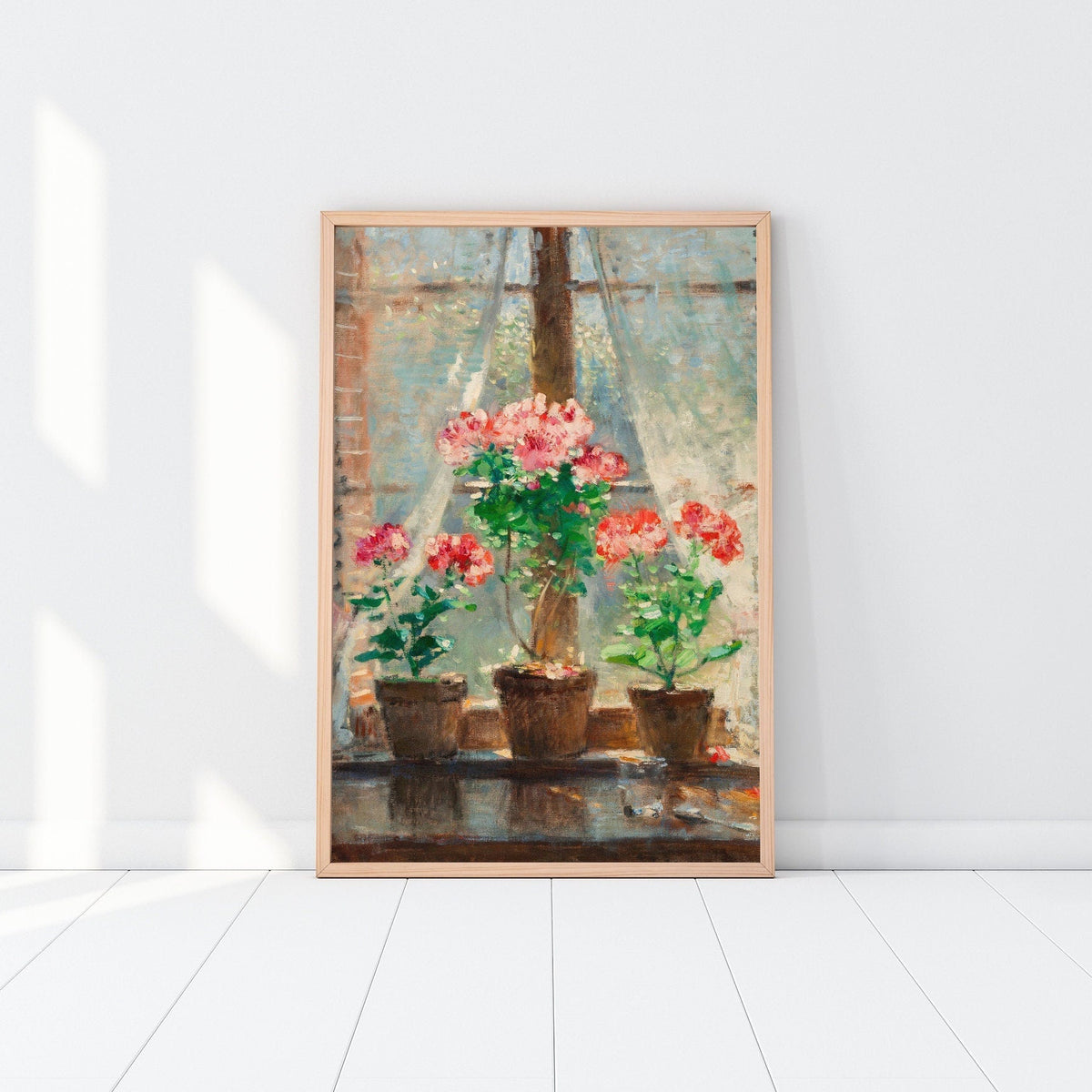 Framed print of potted plants, resting against a white wall in a wooden picture frame.