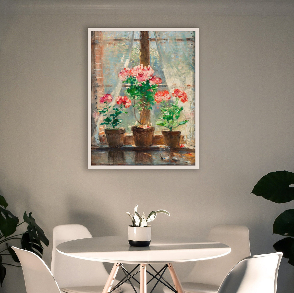 Framed print of potted flowers, on a wall above a dining table with chairs.