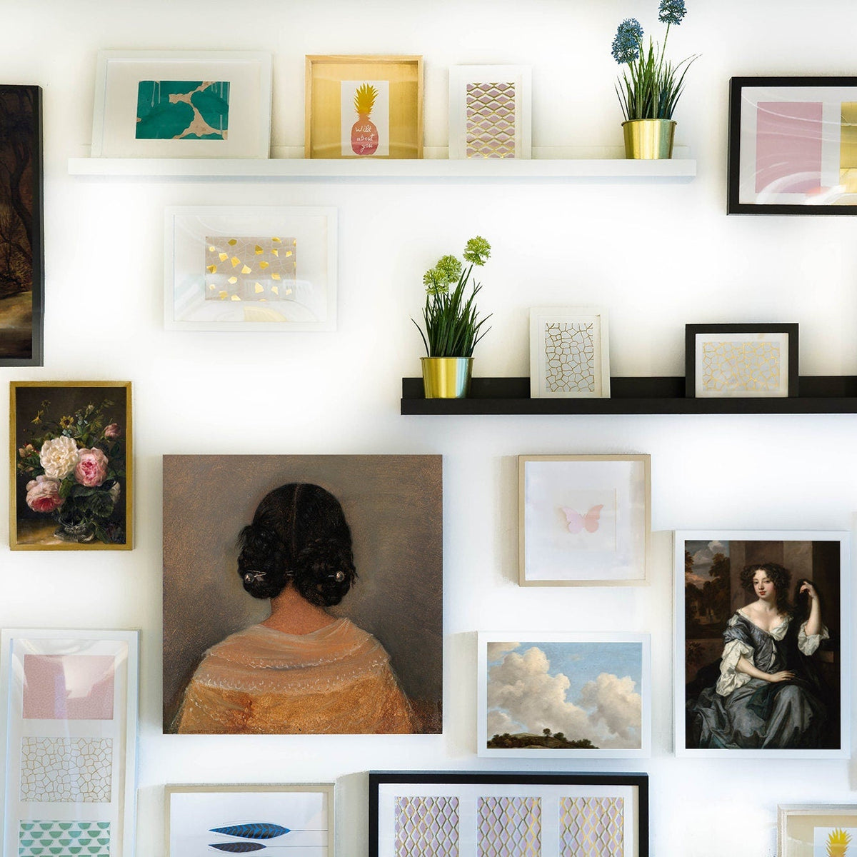 Framed artwork of a woman from behind with dark hair on a light grey background hung in a white frame as part of a gallery wall.