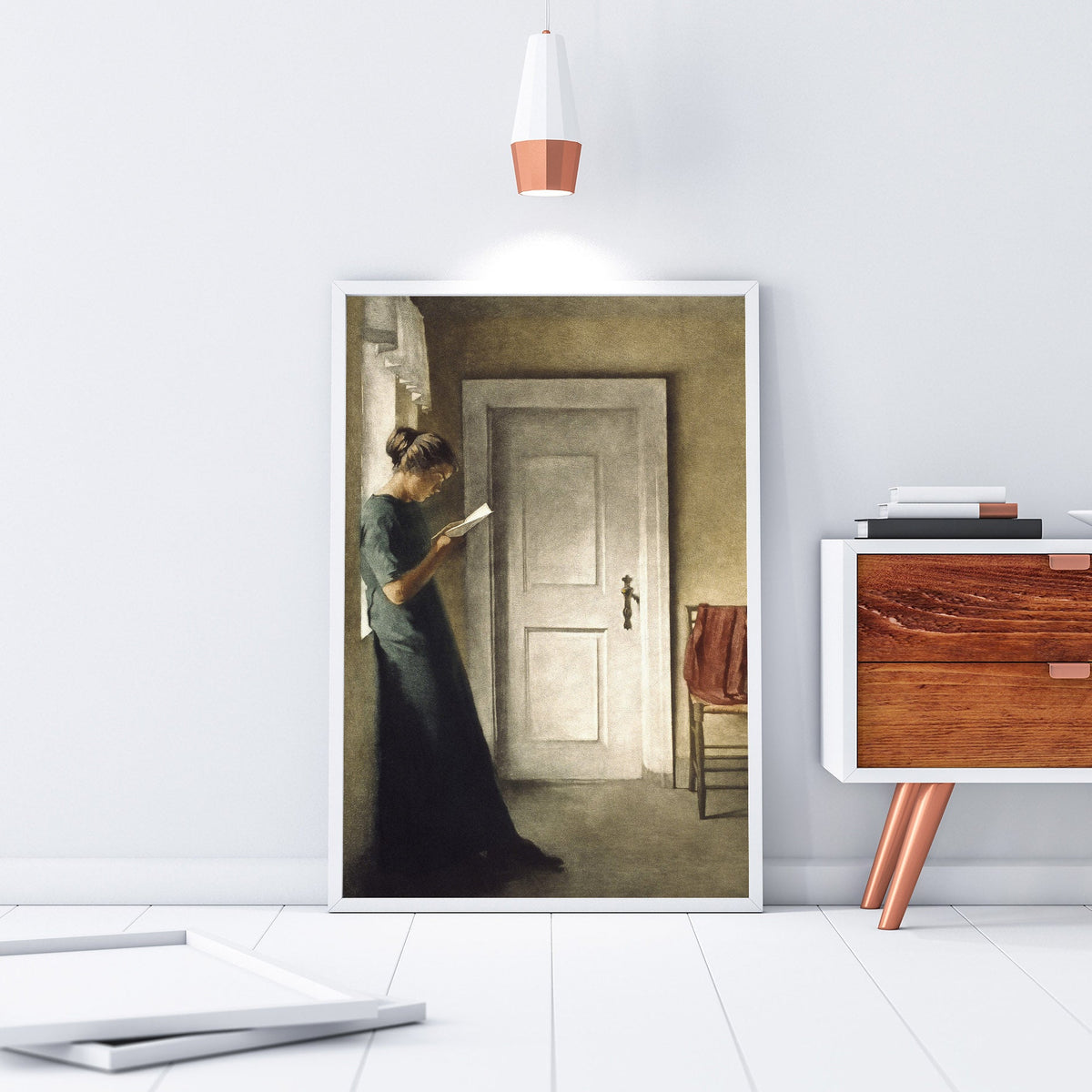Framed artwork of a woman in a room with a wooden cabinet and pendant light.