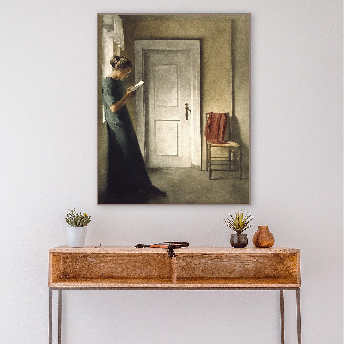 Wooden console table with decorative items against a white wall with a framed painting.