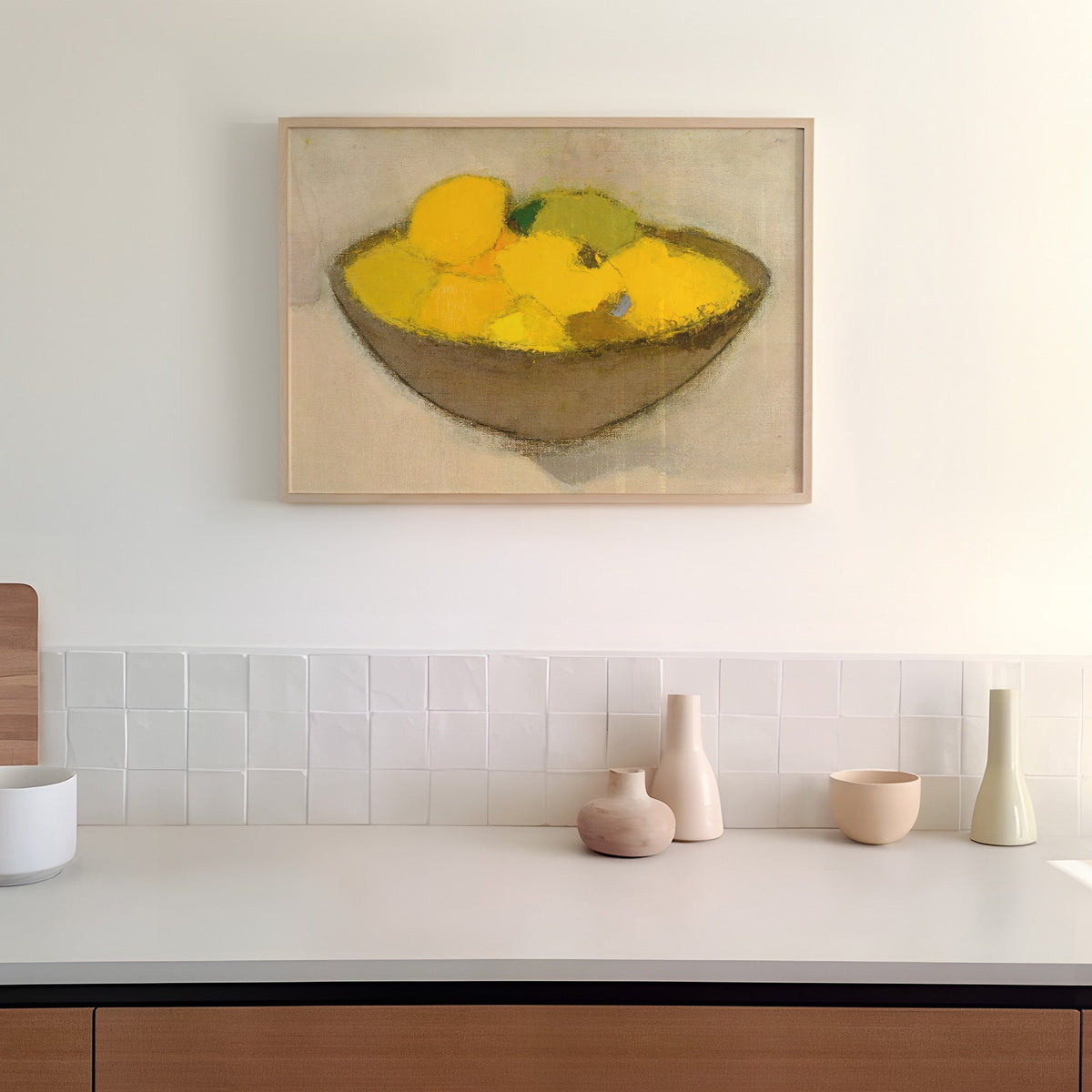Framed print of a bowl of lemons on a wall above a kitchen counter.