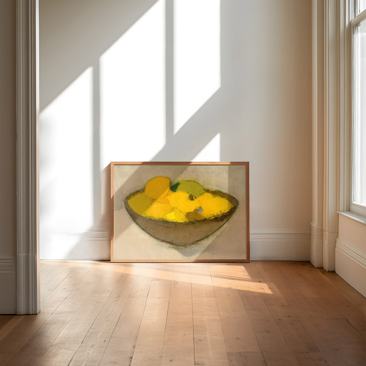 Framed artwork of a still life of a bowl of lemons on a wooden floor in a bright room.