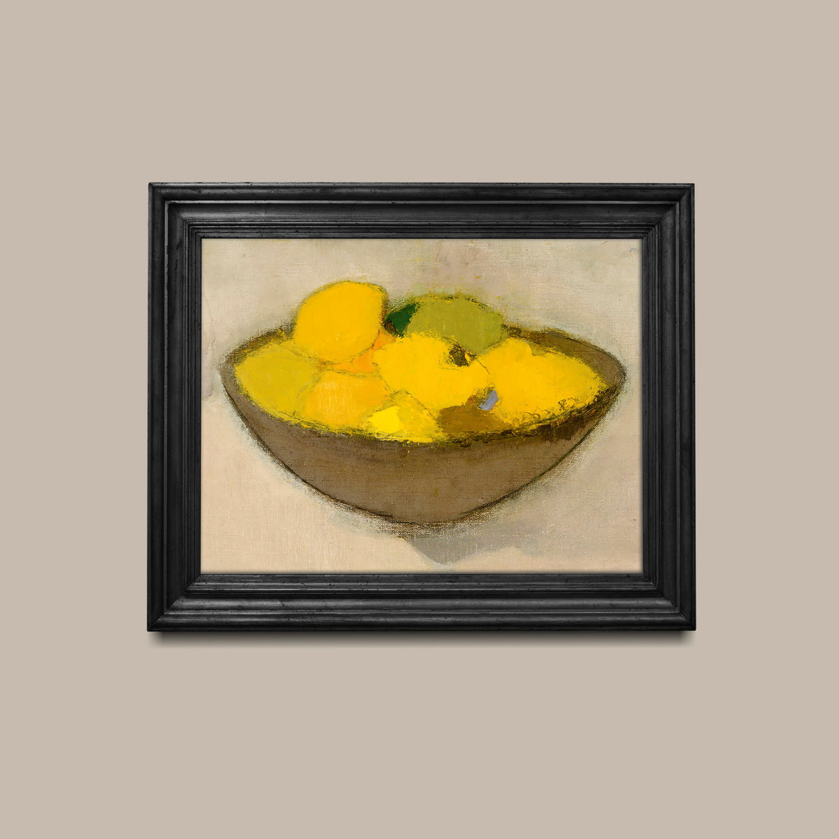 Framed artwork of a still life of lemons in a bowl on a beige wall in a black picture frame.