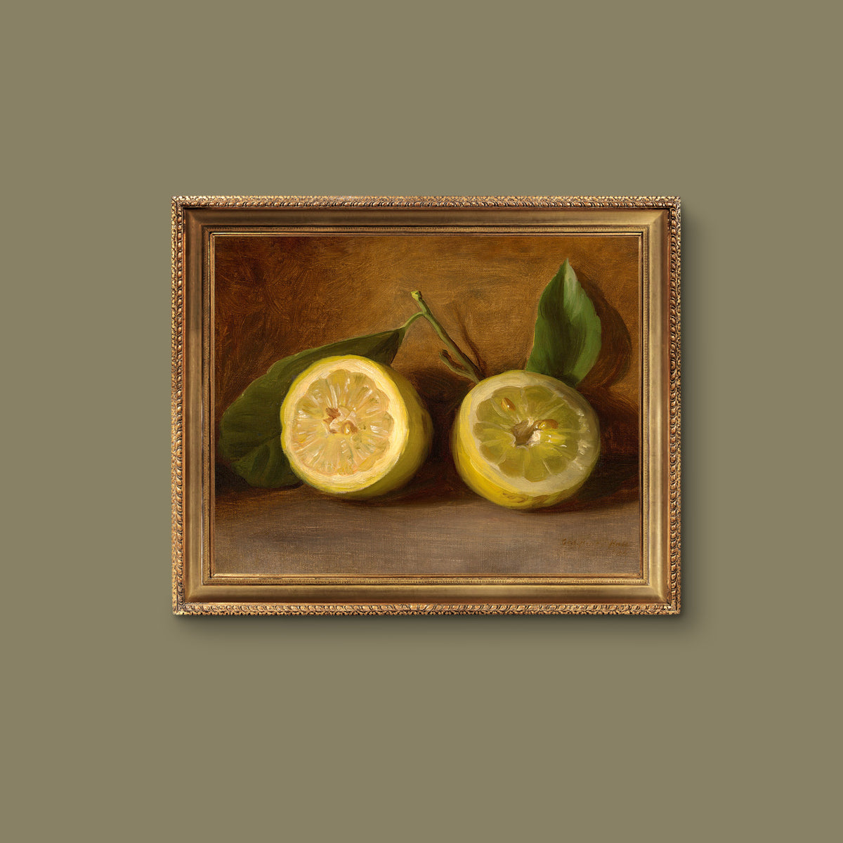 A fine art print of a 19th-century oil still-life painting of a halved lemon. The print is displayed in a gold picture frame hanging on a green wall.