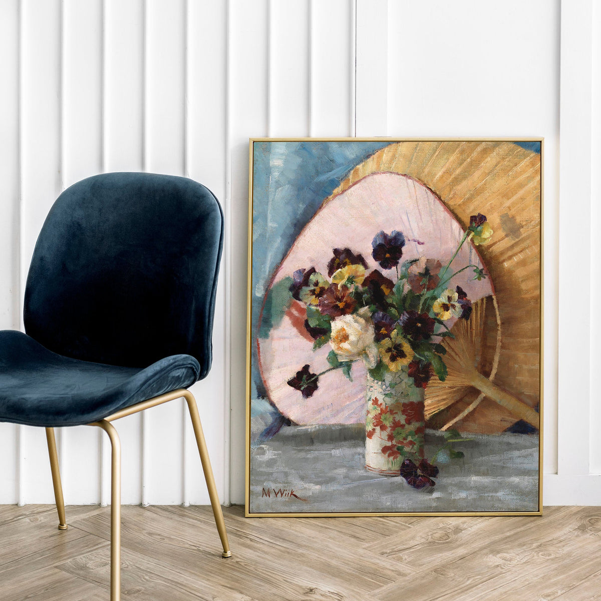 Framed artwork of a floral arrangement leaning against a wall next to a dark blue chair.