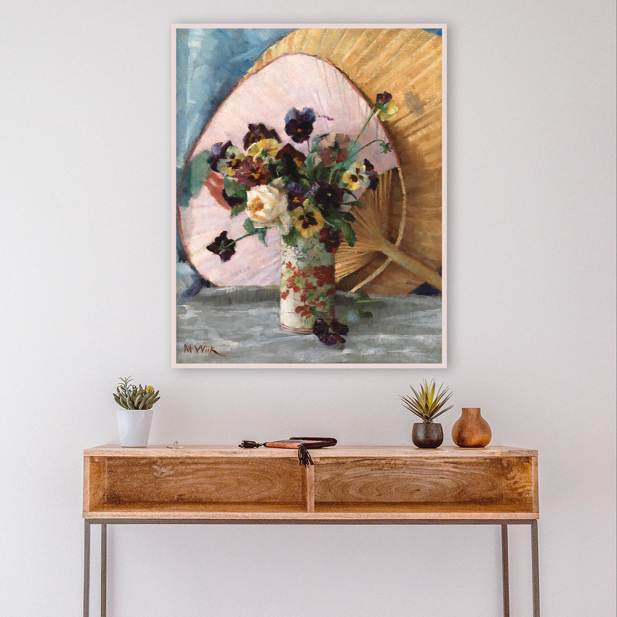 Wooden console table with decorative items against a white wall with a framed floral still-life fine art print above.