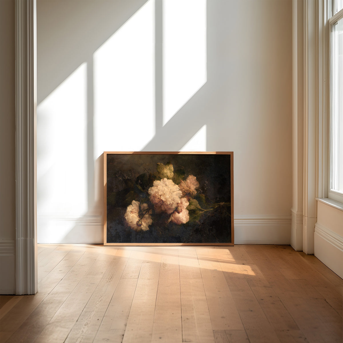 Framed artwork resting against a wall in a room with sunlight streaming through windows