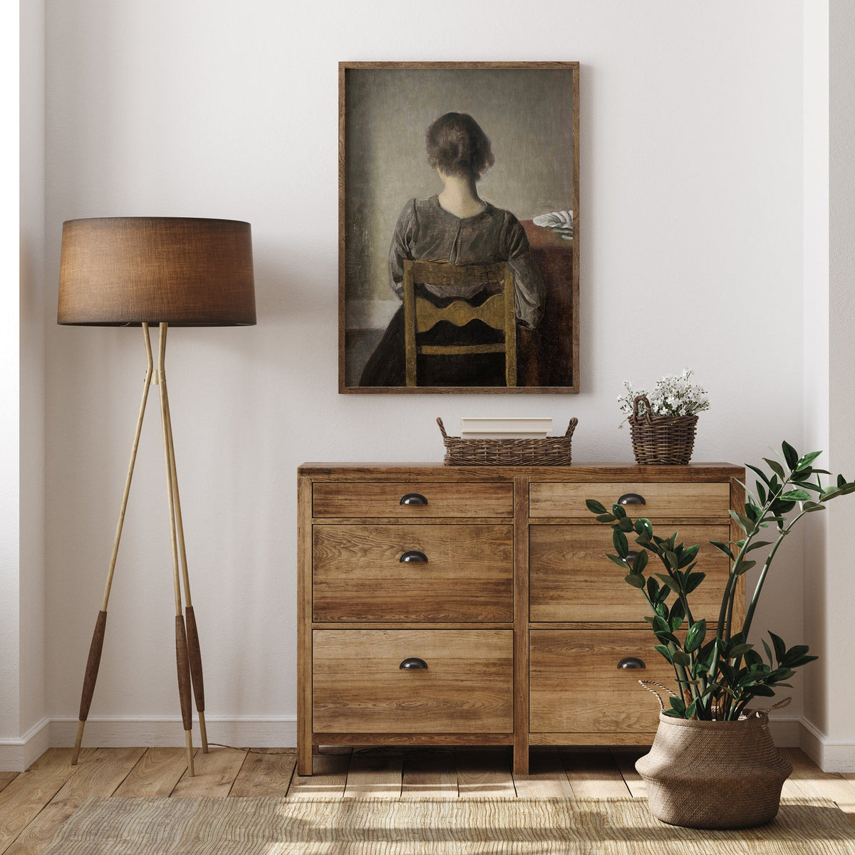 Wooden dresser with a lamp, plant, and framed portrait in a room.