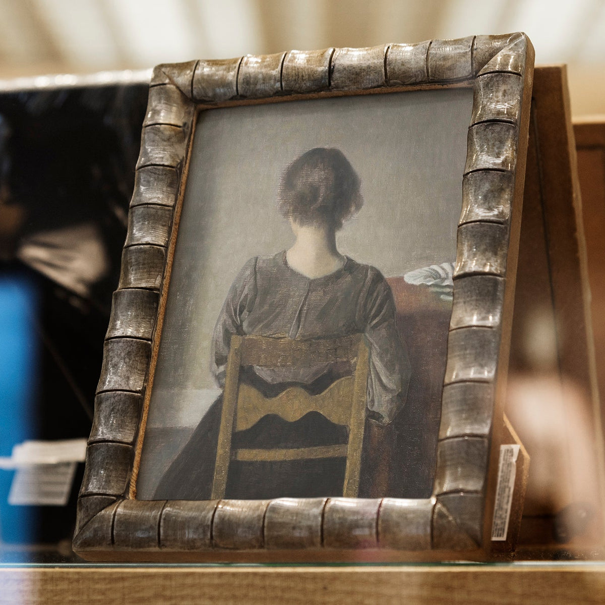 A painting of a female figure in a decorative frame on a wooden surface