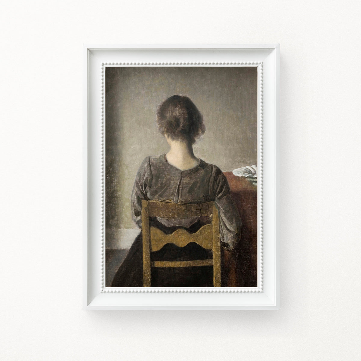 Framed artwork of a woman sitting on a chair with a neutral background