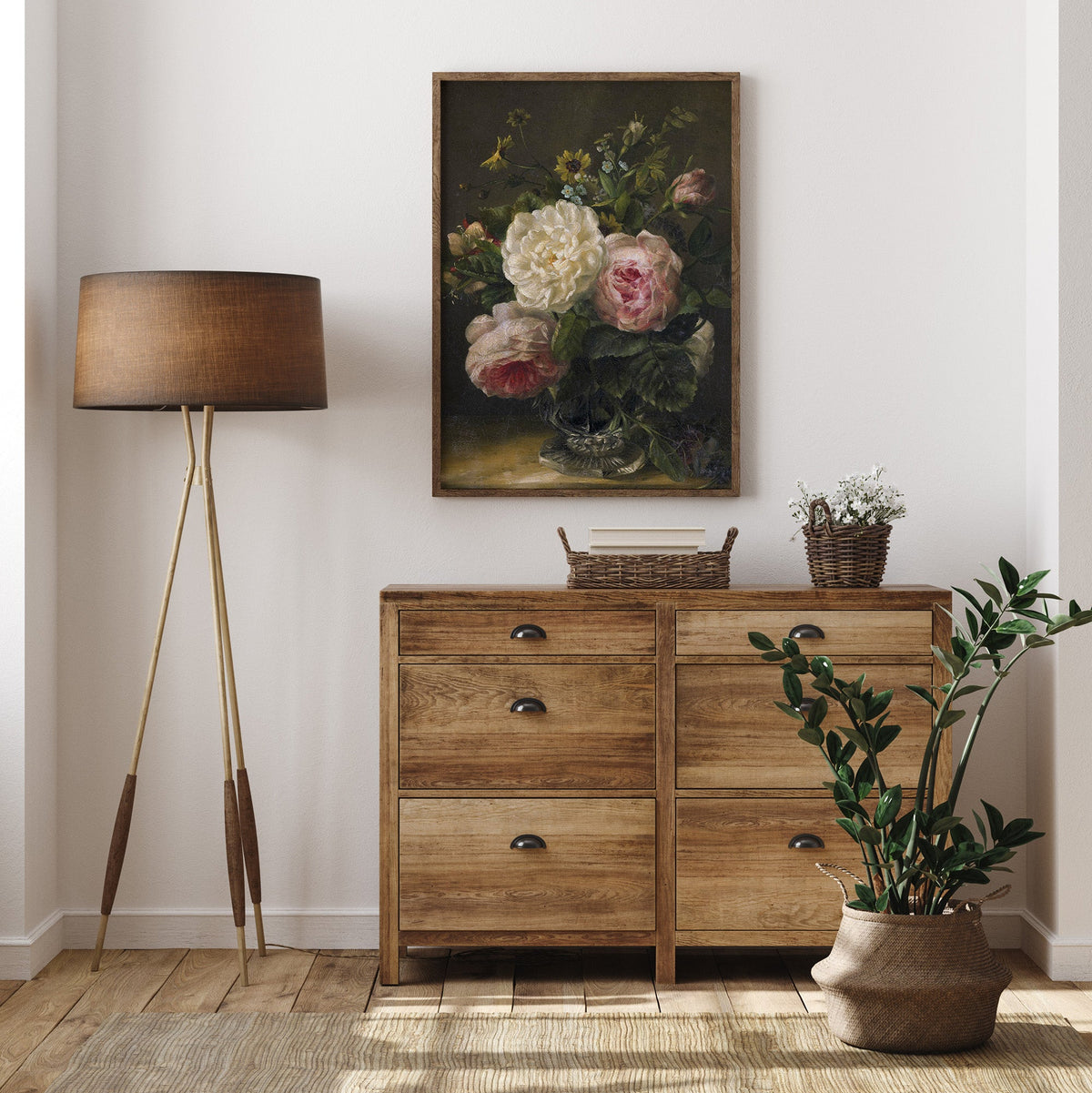 Wooden dresser with a lamp, plant, and floral print in a room.