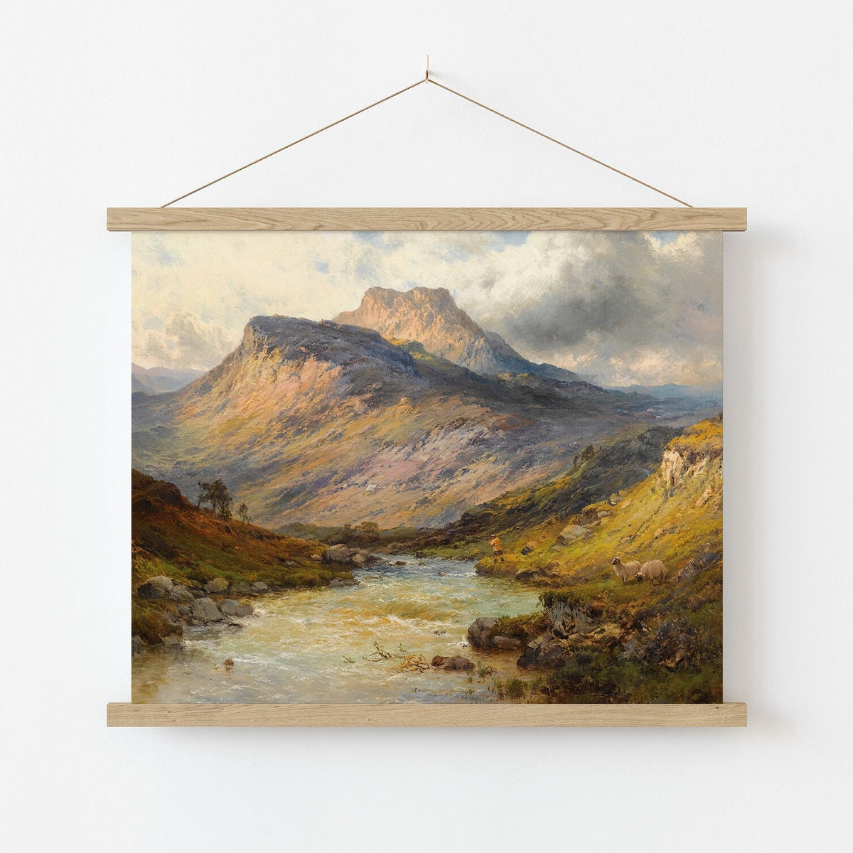 A fine art print of an oil painting depicting dramatic scenery and beautiful sunlight hitting the hills around Ben Lomond in Scotland. A fisherman is fishing on the riverbank. The print is displayed in a wooden poster hanger.