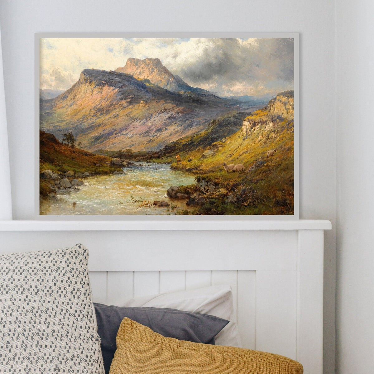 Framed landscape print of a mountainous scene with a river on a wall above a bed.