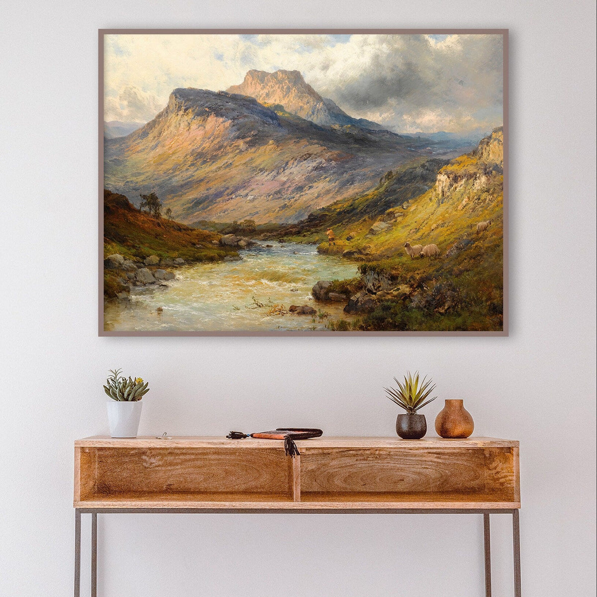 A fine art print of a Scottish landscape. The print is displayed above a side table in a hall.