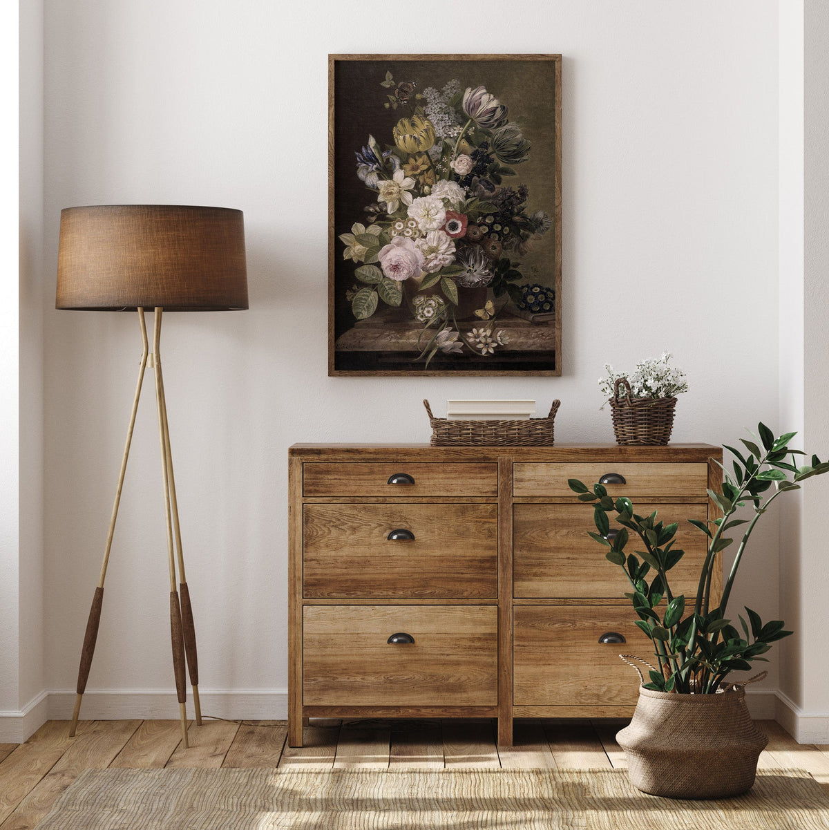 Wooden dresser with a lamp, plant, and floral painting in a room.