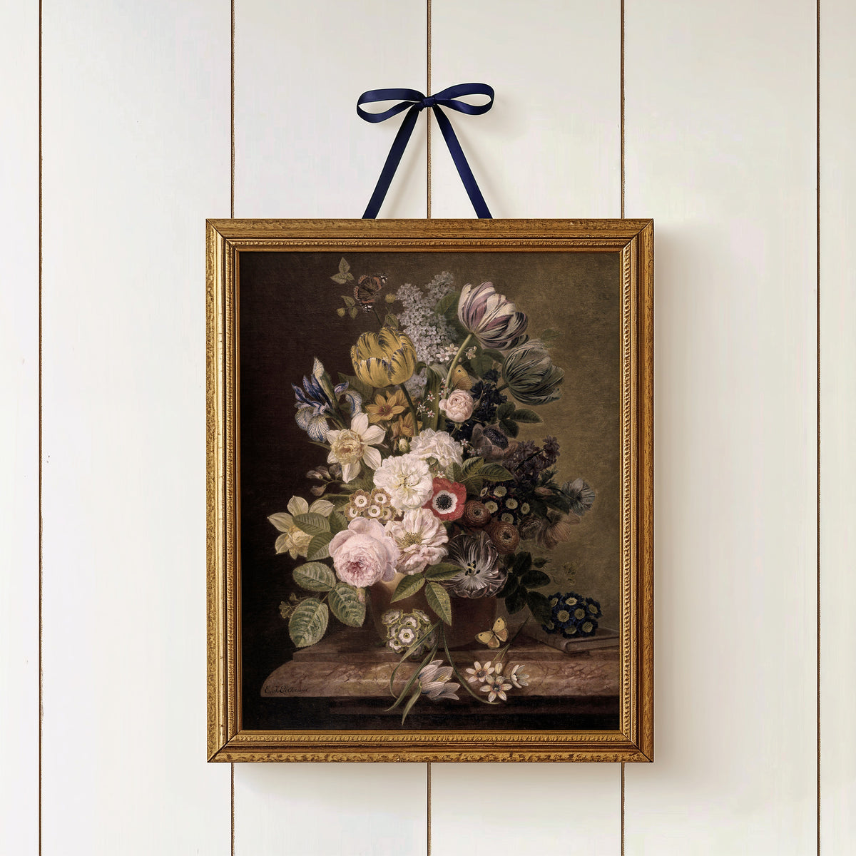 Framed floral print with a blue ribbon on a white paneled wall