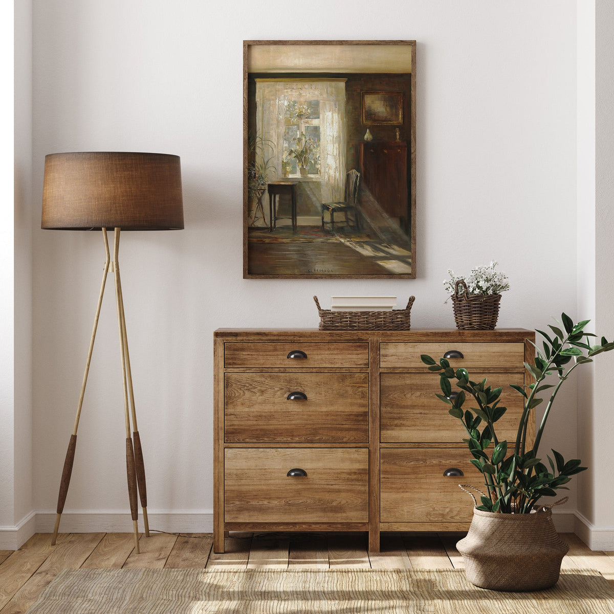 Wooden dresser with a lamp, mirror, and plant, and a print of a room interior, in a room setting.