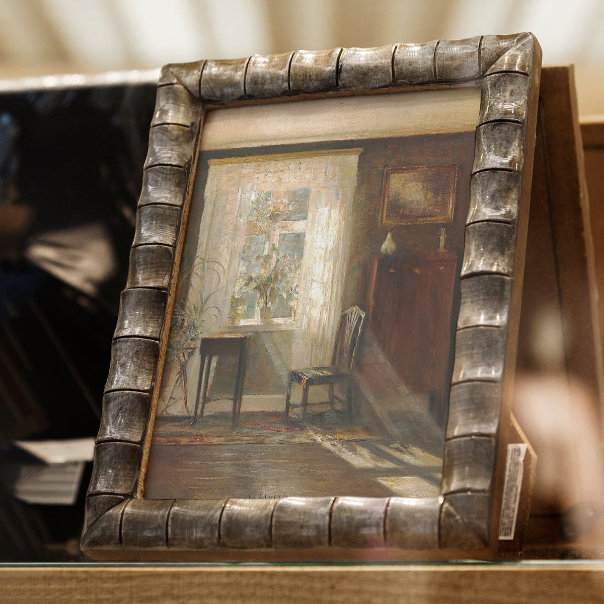 Decorative framed print on a wooden shelf, with a blurred background.